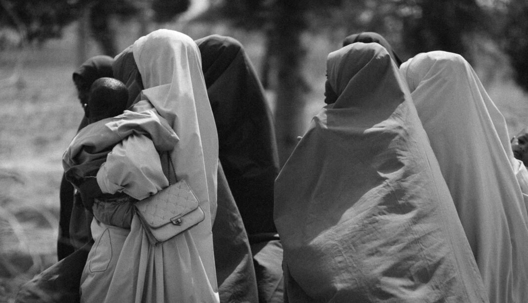 Meloni’s school burqa ban plan puts Italy on Europe’s face-covering map Group of women in traditional attire walking outdoors, captured in black and white.
