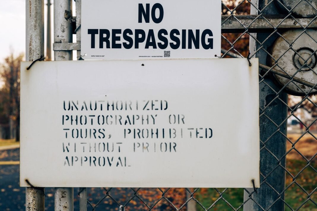 DOJ tells federal court White House access is “a privilege, not a right” A warning sign on a metal fence prohibiting trespassing and unauthorized activities.
