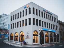 Exterior of contemporary building of bank with arched passages near asphalt road in evening