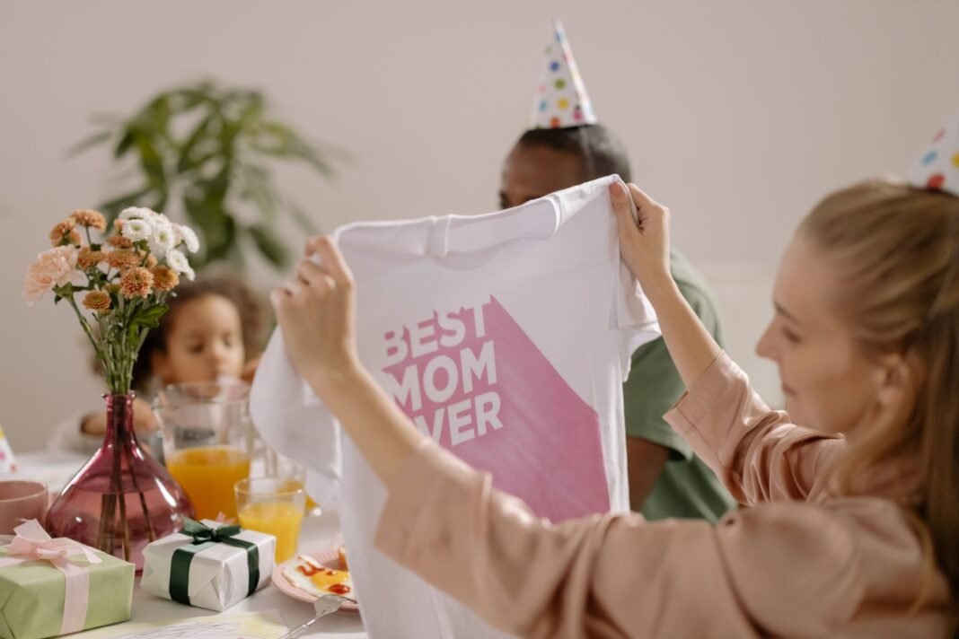 Meg Ryan: ordinary people can change mothers’ and children’s lives A joyful indoor Mother's Day celebration featuring a family with a 'Best Mom Ever' shirt.