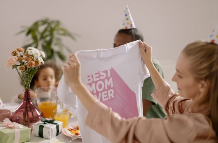 A joyful indoor Mother's Day celebration featuring a family with a 'Best Mom Ever' shirt.
